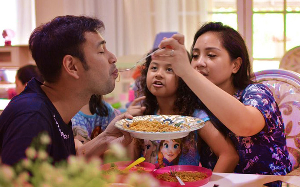 ibu ayah dan anak sedang makan bersuap